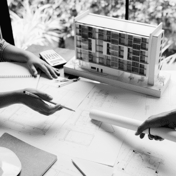 Manos realizando planos junto a edificio